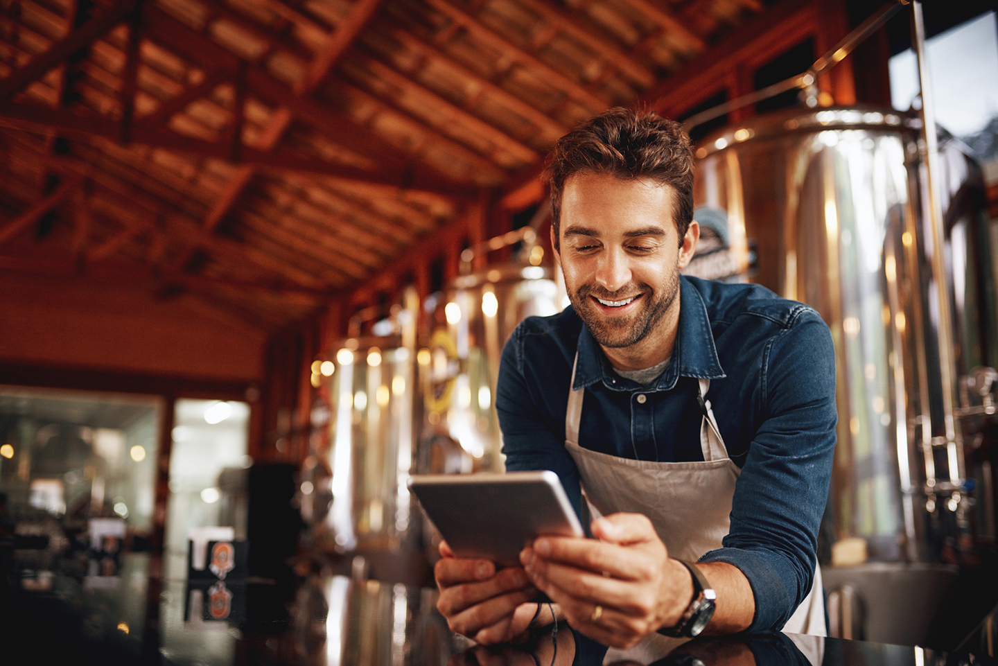 Man on tablet in front of distillery tanks