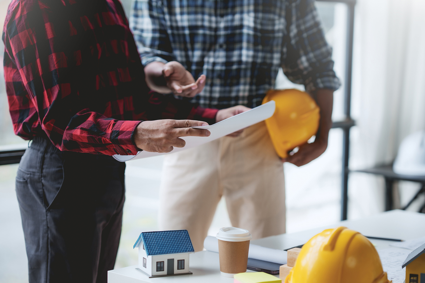 Workers with hardhats dicussing blueprints